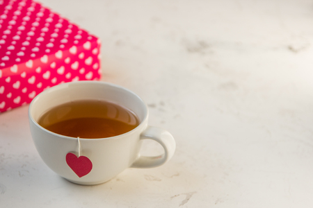 Cup of tea with heart teabag and gift boxes.の写真素材