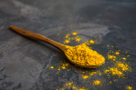 Turmeric powder on a wooden spoon, copy space.の写真素材