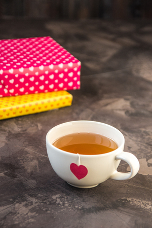 Cup of tea with heart teabag and gift boxes.の写真素材