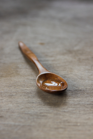 Honey in a wooden spoon on a old table.の写真素材