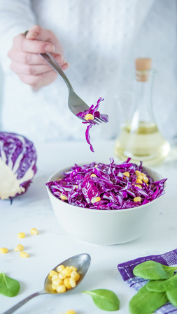Salad of red cabbage and corn. Woman's hand holds fork with salad.の写真素材