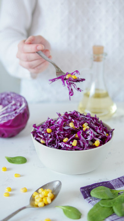 Salad of red cabbage and corn. Woman's hand holds fork with salad.の写真素材