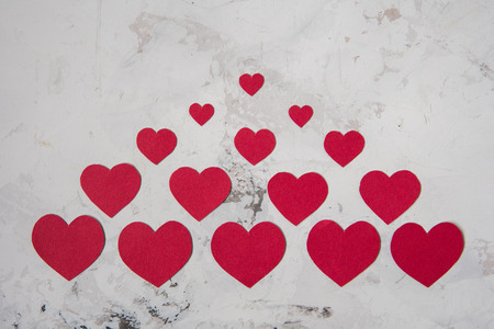 Red paper hearts on a white texture background.の写真素材