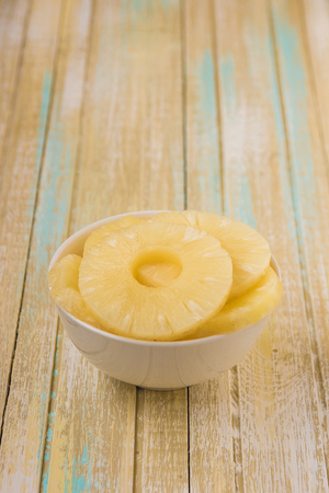 Pineapple rings in a white bowl. Canned ananas slices, copy space.の写真素材
