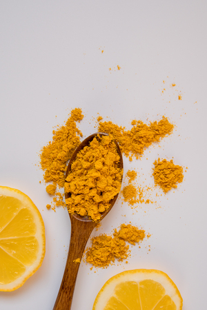 Turmeric in a wooden spoon and two lemon slices top view.の写真素材