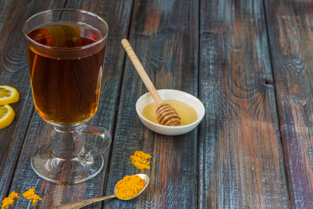 Tea, turmeric, honey and lemon on a wooden dark background.の写真素材
