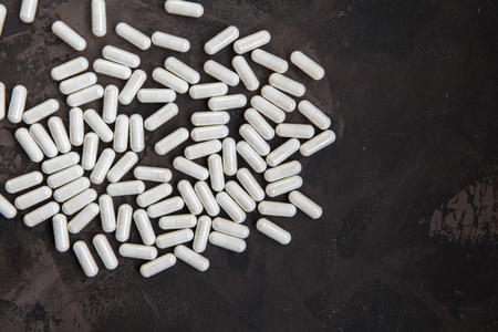 White madicine capsules contain vitamin, drug or nutritional supplement.の写真素材
