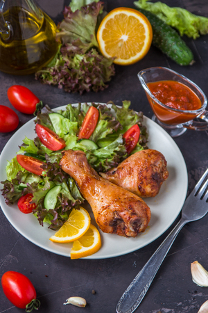 Fried chicken legs and fresh salad on a dark background.の写真素材