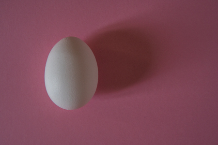 White egg on a pink background top view.の写真素材