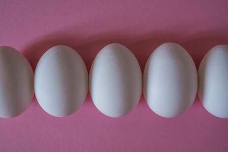 White eggs on a pink background top view.の写真素材