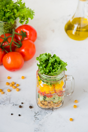 Salad in a jar. Homemade healthy salad from chickpea, tomato, yellow paprika, cucumber and green lettuce.の写真素材