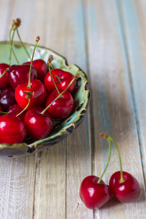 Cherries in a plate on a wooden table. Fresh red cherry.の写真素材