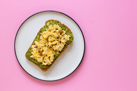 Egg on whole wheat bread with avocado, pink background top view.の写真素材
