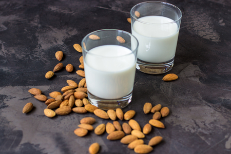 Almond milk in glass and almonds nuts on a dark background.の写真素材