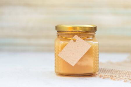 Honey in jar with empty paper label for your text or logoの写真素材