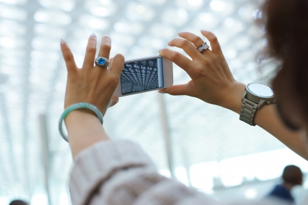 a woman taking photo with mobile phone in airport, shenzhen, chinaの写真素材