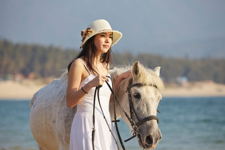 a Chinese woman walking with horse on beach