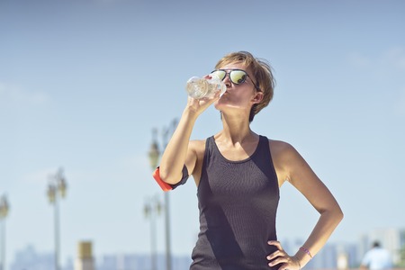 young asian woman drinking water after joggingの写真素材