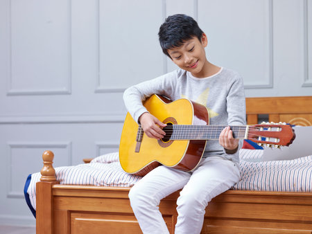 teenage learning and practicing playing guitar at home