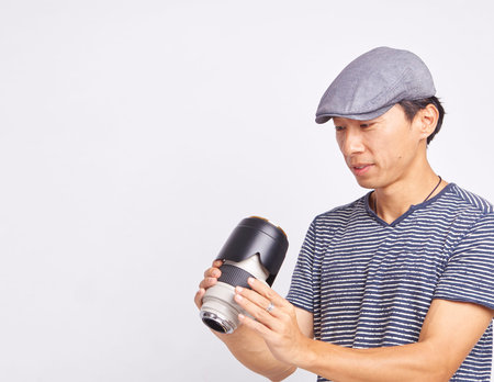 studio shot of Asian photographer checking lens