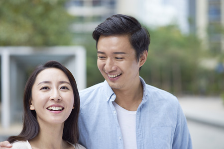 Portrait of young Chinese couple standing smiling outdoorの写真素材