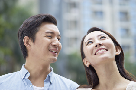 portrait of young Chinese couple standing & smiling outdoor in gardenの写真素材
