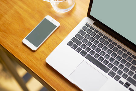 Laptop, smart phone and a glass of water on coffee shop table