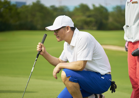 Asian golfer crouching aiming before puttingの写真素材