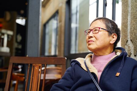 portrait of senior Asian woman sitting alone in cafeの写真素材
