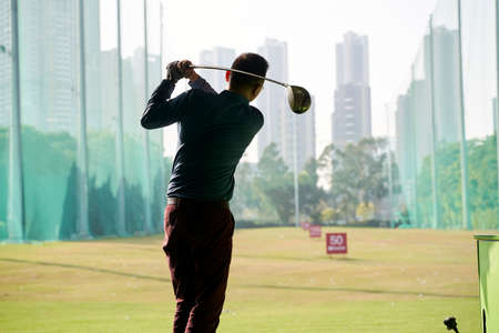 rear view of Asian man practicing golf swingの写真素材