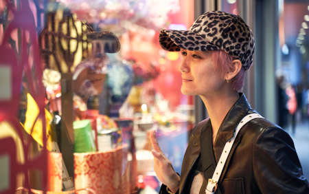 portrait of Asian fashion beauty smiling and looking into store window when shopping in the holidayの写真素材