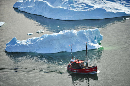 Greenland. Giant icebergs in the area of the village Ilulissat with fishing boatの写真素材