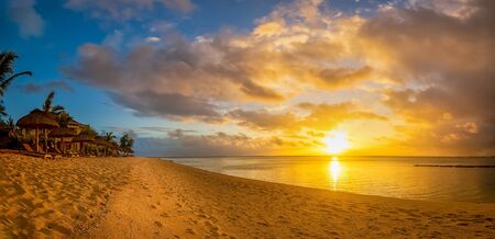 Beautiful sunset at Mauritius, Le Morne at a beach with palms nearby the ocean.の写真素材