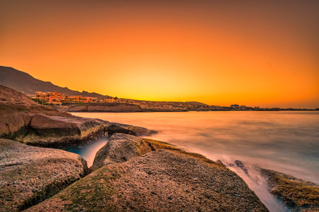 Warm colors at an impressive sunrise on stones nearby the sea at Tenerife.