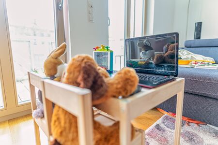 Home office - new working oportunities symbolically shot with an on a notebook working stuffed dog and in front of a toy laptop sitting rabbit, new lifestyle in 2020.の写真素材