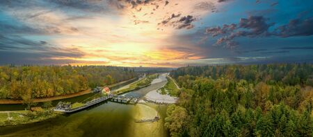 Beautiful natural scenery of river in southern bavaria with a green forest and mountains in background, aerial view drone shotの写真素材
