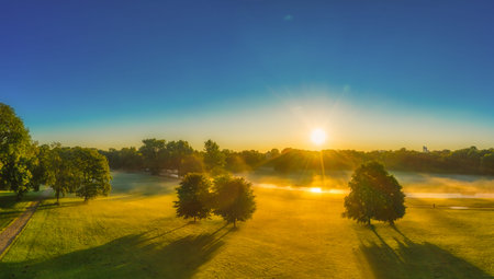 Sun is shining over Munich Enlish Garden, early in the morning, sunbeams are falling through the...
