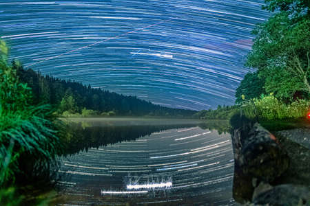 Long Exposure Startrails over an idyllic lake with star reflections in the water - wonderful star clear night.の写真素材