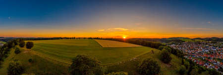 Sunset panorama of a wide farm land with cows in the foreground in a total view, beautiful landscape shot by a drone.の写真素材