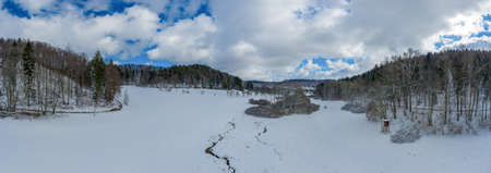 Idyllic winter creek at a meadow between a forest with lot of snow, wonderful white season photo.の写真素材