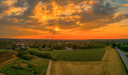 Glowing sunset next to a village in orange colors, wonderful morning hour.の写真素材