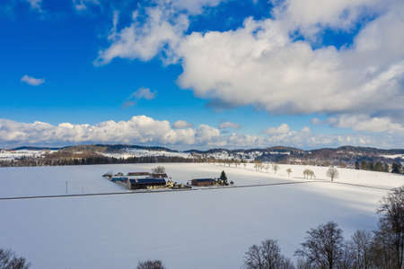 An idyllic courtyard in the open winter space, surrounded by snow with hills in the background.の写真素材