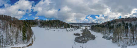 Idyllic winter pano in germany, swabian alb with snowy forest trees at the blue sky day.の写真素材