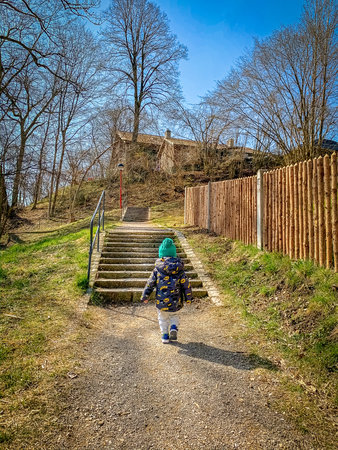The one-year child climbs up the stairs. Cute baby boy in hat plays on the stairs. The concept of...