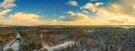 Winter fairytail view over a idyllic house in the middle of a white snow covered forest with green fir trees, aerial panoramic view of the winter seasonの写真素材