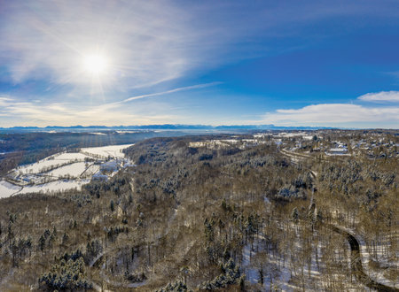 Leading curvy road to the famous monastery Kloster Schaeftlarn in Bavaria in Germany at the beautiful snowy season, captured from above at a sunny day.の写真素材