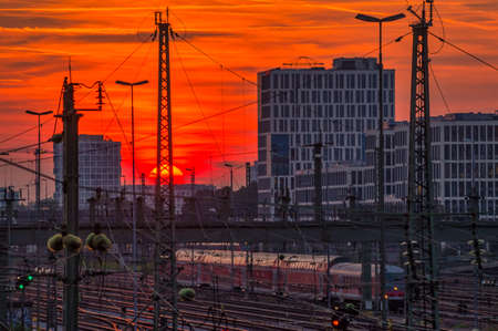 Impressive sunset over Munich and a business district in the background with the view over a railway with a driving train at the late evening.の写真素材