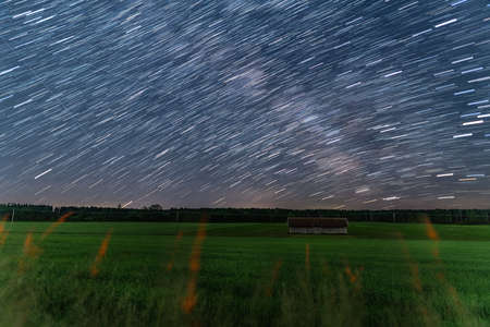 Startrails over a little hut at a farmland at the starry night, beautiful nature and concept for motion of the earth.の写真素材