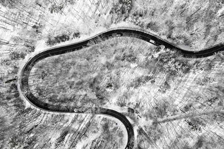 Aerial view at a curvy road as topdown shot in the winter with the street surrounded by the white clean snow.の写真素材