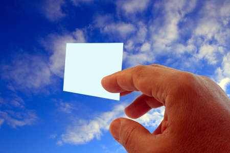 hand giving blank visit card on blue sky with cloudsの写真素材